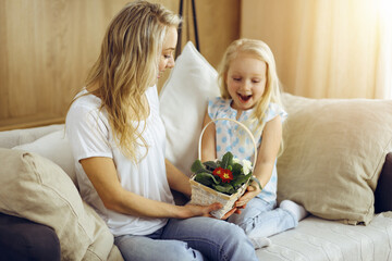 Obraz na płótnie Canvas Happy mother day. Child daughter congratulates mom and gives her basket of spring flowers. Family concept