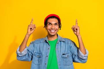 Photo of funky nice guy man wear stylish denim clothes piercing earrings two arms direct empty space isolated on yellow color background