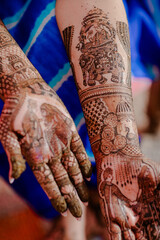 Mehndi master drawing henna tattoo on female