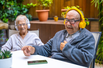 Old man listening to music with headphones in a geriatric
