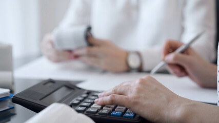 Two accountants use a calculator and laptop computer for counting taxes or revenue balance. Business, audit, and taxes concepts