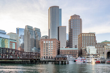 Rusty bridge to the embankment with moored ferries and other ships and boats in the center of the downtown of old Boston with skyscrapers