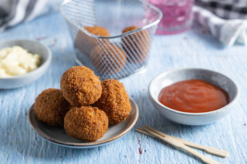 Fried meatballs in a bowl with ketchup on the side.