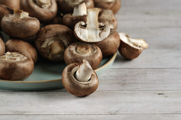 Selective focus on fresh organic brown champignon mushrooms on a plate. Daylight, blurry background. Copy space