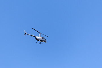 Fototapeta na wymiar A gray helicopter crosses the blue sky with clouds. Transportation. Urban.