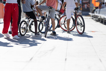 Group of teens kids with bicycles, one person standing on a ramp
