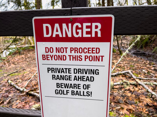 Close up view of a private driving range warning sign at the perimeter of a large country club