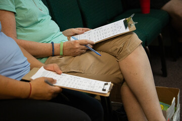 Woman holding clipboard and worksheets during women's Bible study