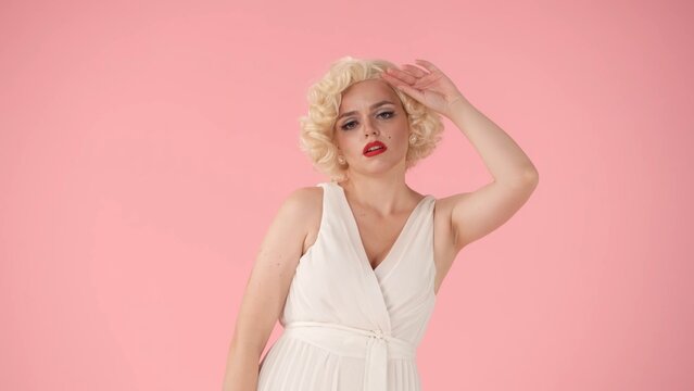 Shopping can be tiring. Young tired woman wiping sweat from forehead. Woman in the image of Marilyn Monroe in studio on pink background. Shopping concept.