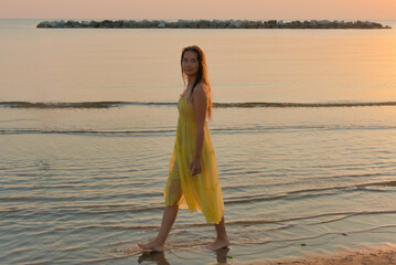 A young woman walks along the beach at sunrise and shares her adventurous journey