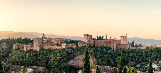 Panorama of the Arabian fortress Alhambra, perched atop a hill in Granada, Spain, bathes in the ethereal beauty of a sunrise