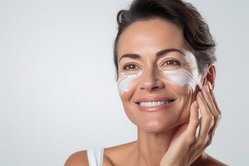 Fight against aging skin. happy woman 40-45 years old applies cream to her face, close-up, skin care, beauty and health. Prevention of skin aging, skin rejuvenation cream.