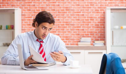 Young handsome employee working in the office