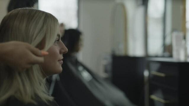 Rack focus of hairdressers styling hair of customers in salon / Cedar Hills, Utah, United States