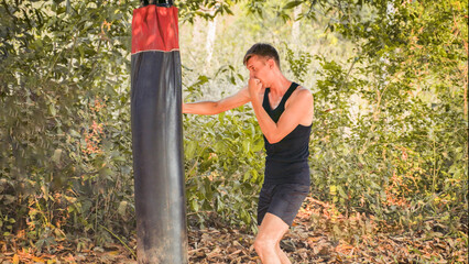 sportsman is striking a punching bag against the backdrop of the jungle