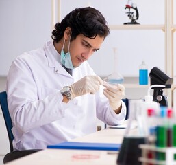 Young handsome chemist working in the lab