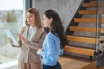 Copy space shot of two young businesswomen walking to a meeting together and looking at data on a...