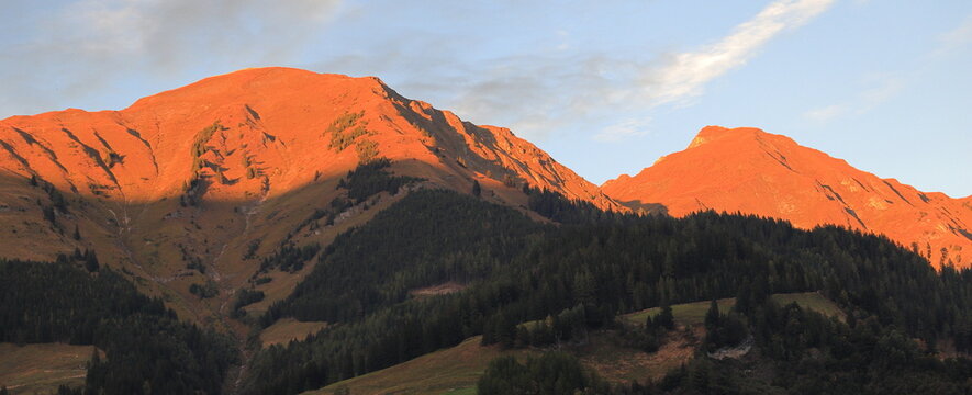 Mountains illuminated by a red sunset. A valley in the shadow, out of the reach of the sun's rays. Hohe Tauern National Park - Rauris