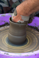 Hands of a potter, creating an earthen jar on the circle.