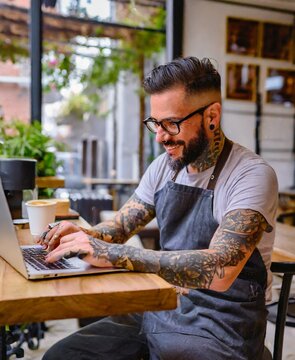 Coffee barista working with laptop at coffee shop