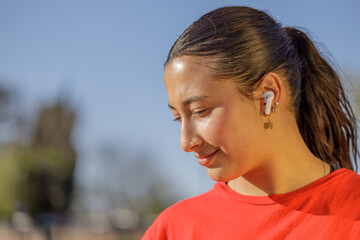 Close-up portrait of a latin girl in red t-shirt with headphones.