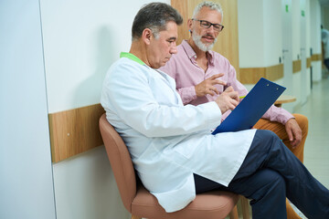 Adult men communicate in a bright hospital corridor