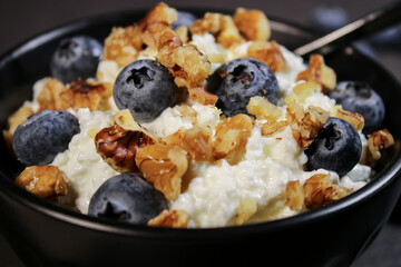 Cottage cheese with fresh blueberries in black bowl, hight protein dessert