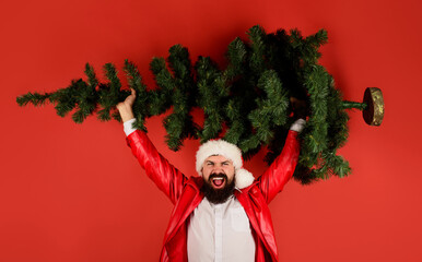 Fototapeta na wymiar Merry Christmas and Happy New year. Delivery man in Santa hat with Christmas tree. Bearded businessman in red leather jacket with fir-tree. Winter holidays celebration. Preparing for new year party.