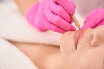 Obraz na płótnie Canvas Marking a woman lips before a tattoo procedure