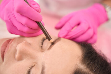 Master makes markings before procedure of tattooing eyebrows of client