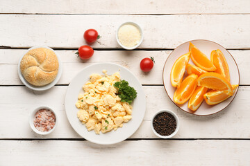 Composition with plate of delicious scrambled eggs with ingredients on white wooden background