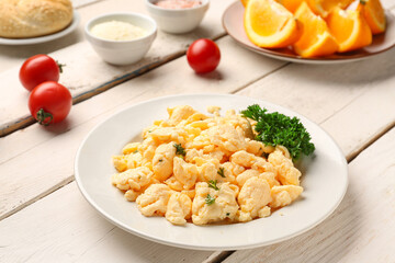 Plate of delicious scrambled eggs with ingredients on  white wooden background
