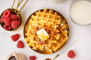 Tasty waffles with raspberries, maple syrup and glass of milk on white background
