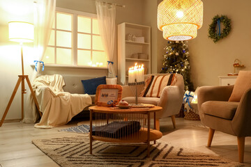 Interior of living room decorated for Hannukah with sofa, glowing lamps and table at night
