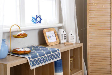 Greeting card for Hannukah with candle holders and donuts on shelf in room
