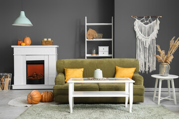Interior of living room with electric fireplace, sofa and pumpkins