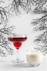 Glasses of delicious cocktails with branches for Halloween celebration on white background
