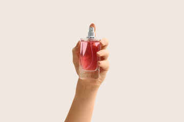 Female hand with bottle of elegant perfume on white background