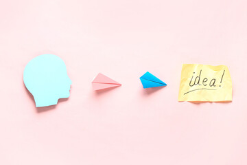 Human head, paper planes and sheet with word IDEA on pink background. Business idea concept