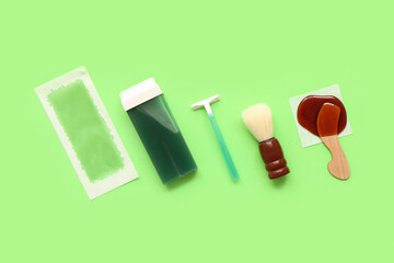 Safety razor with liposoluble wax cartridge, strip and brush on green background