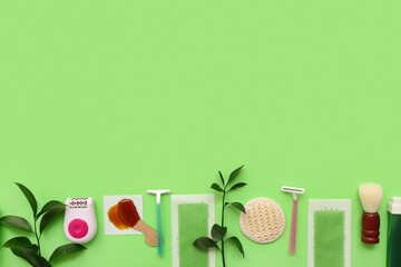 Different supplies for hair removal with plant branches on green background