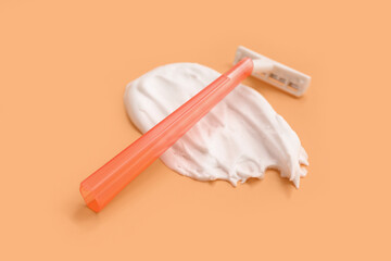 Safety razor and shaving foam on orange background