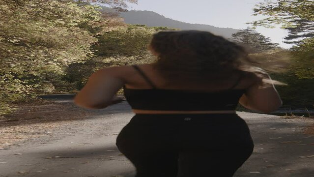 Slow motion rear view tracking shot of teenage girl running on park path in autumn - vertical / American Fork Canyon, Utah, United States