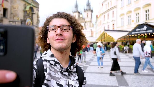 Prague,Czech Republic,August 4,2023. A young Caucasian man takes a selfie with one of the most beautiful and iconic views - the old town square with the astronomical clock and church in the background