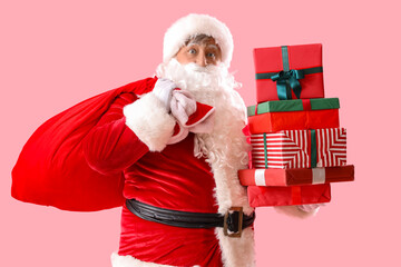 Santa Claus with bag and Christmas gift boxes on pink background