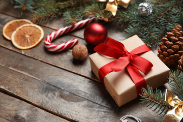 Beautiful fir branches with Christmas decorations and gift box on brown wooden background
