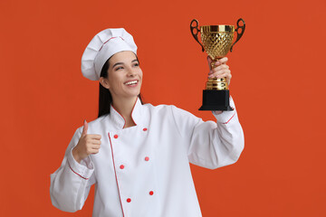 Female chef with gold cup showing thumb-up on orange background