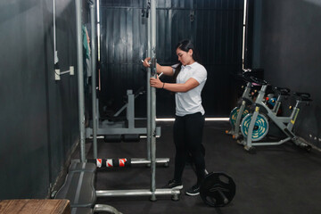 Female trainer preparing the rack for squats in the gym.