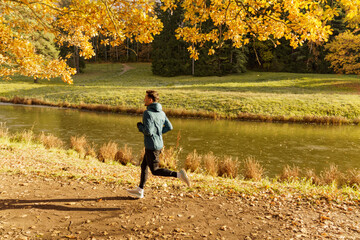 Healthy person training in the afternoon in the autumn cold season. An athlete in sports shoes and warm clothes for fitness. Jogging, warm-up every day, healthy lifestyle.