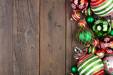 Christmas side border of red, green and white ornaments. Above view on a dark wood background. Copy space.